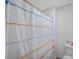 Bathroom with a white shower curtain with blue, orange, and red yarn-like stripes at 7641 Sail Clover Ln, Zephyrhills, FL 33540