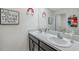 Bright bathroom features a double sink vanity with gray cabinets and framed inspirational art at 7641 Sail Clover Ln, Zephyrhills, FL 33540