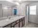 Clean bathroom featuring double sinks, shower, and an adjacent walk-in closet at 7641 Sail Clover Ln, Zephyrhills, FL 33540