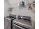 Modern laundry room with front-load washer and dryer and storage shelves at 7641 Sail Clover Ln, Zephyrhills, FL 33540