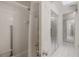 Clean bathroom showcasing white tile, a shower with grab bars, and mirrored closet doors at 7902 Heather Ct, Tampa, FL 33634