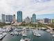 An aerial view showcases boats docked at a marina with luxurious condominiums against a backdrop of a vibrant city skyline at 100 Beach Ne Dr # 301, St Petersburg, FL 33701