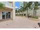 Expansive outdoor patio showcasing the brick flooring, beautiful palm trees, and lush landscaping at 100 Beach Ne Dr # 301, St Petersburg, FL 33701