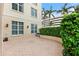 View of outdoor patio area with brick flooring, lush landscaping and building exterior with classic lighting at 100 Beach Ne Dr # 301, St Petersburg, FL 33701