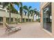Elegant outdoor patio with brick flooring, palm trees, lounge seating, and well-maintained landscaping at 100 Beach Ne Dr # 301, St Petersburg, FL 33701