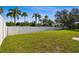 The backyard features a white fence, lush green grass, and tropical palm trees at 10244 Shadow Branch Dr, Tampa, FL 33647