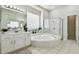 Bright bathroom featuring soaking tub, glass shower, and dual white vanities at 10244 Shadow Branch Dr, Tampa, FL 33647