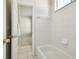 Clean white bathroom features white tiled shower over tub and doorway to adjacent carpeted room at 10244 Shadow Branch Dr, Tampa, FL 33647