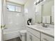 Bright bathroom features a bathtub with shower, a window, and a modern sink vanity at 10244 Shadow Branch Dr, Tampa, FL 33647