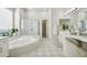 Light-filled bathroom boasts soaking tub, separate glass shower and white vanity at 10244 Shadow Branch Dr, Tampa, FL 33647