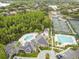 Aerial view of a community pool, clubhouse, and tennis courts surrounded by green trees, offering a variety of amenities at 10244 Shadow Branch Dr, Tampa, FL 33647