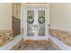 Front door with glass inserts and decorative wreaths, complemented by stone accents and a welcoming doormat at 10310 Carroll Cove Pl, Tampa, FL 33612
