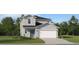 Two-story home featuring a teal front door, lush green lawn, and a two-car garage at 11708 Brae Way, Dade City, FL 33525