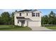 Charming two-story home featuring a gray color scheme, green door, and an attached two-car garage at 11729 Brae Way, Dade City, FL 33525