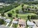 Aerial view of a single-story home with a screen-enclosed pool, set against a backdrop of lush golf course views at 1224 W Del Webb Blvd, Sun City Center, FL 33573