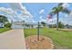 Charming single-story home with well-manicured lawn, colorful landscaping, a palm tree, and an American flag at 1224 W Del Webb Blvd, Sun City Center, FL 33573