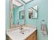 Bright bathroom featuring a single sink vanity, decorative mirrors, and vibrant turquoise walls at 12306 91St Ter, Seminole, FL 33772