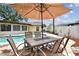 Outdoor patio area featuring a tile-topped table and chairs with an umbrella for shaded dining by the pool at 12306 91St Ter, Seminole, FL 33772