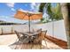 Outdoor patio area featuring a tile-topped table and chairs with an umbrella and white privacy fence at 12306 91St Ter, Seminole, FL 33772