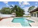 Inviting pool area with brick pavers, an outdoor dining set, and lush tropical landscaping, perfect for relaxation at 12306 91St Ter, Seminole, FL 33772