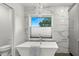 Modern bathroom featuring a standalone tub, marble tile, and window with blind shade at 146 26Th Ne Ave, St Petersburg, FL 33704
