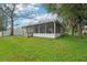 View of the backyard with screened-in porch and lush green lawn, offering a relaxing outdoor retreat at 1502 Marsh Wood Dr, Seffner, FL 33584