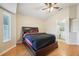 Bedroom featuring wood floors, ceiling fan, large windows, and a bathroom doorway at 1502 Marsh Wood Dr, Seffner, FL 33584