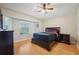 Spacious bedroom with wood floors, a ceiling fan, large windows, and dark wood furniture at 1502 Marsh Wood Dr, Seffner, FL 33584