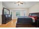 Primary bedroom featuring wood floors, a ceiling fan, large windows, and dark wood furniture at 1502 Marsh Wood Dr, Seffner, FL 33584