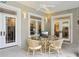 A covered patio features neutral walls, multiple windows, and a glass-topped table with seating for relaxing and dining at 1803 143Rd E Ct, Bradenton, FL 34212