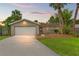 Charming single-story home featuring an attached garage, well-maintained lawn, and mature palm trees against a beautiful sunset sky at 1909 Dover Ct, Oldsmar, FL 34677