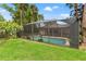An exterior view of the caged-in pool with a well manicured backyard at 1909 Dover Ct, Oldsmar, FL 34677
