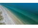 Expansive aerial view of a white sandy beach bordering tranquil turquoise ocean waters at 19531 Gulf Blvd # 306, Indian Shores, FL 33785