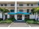 Inviting condominium building entrance featuring a blue awning that reads, Golden Shores, mature landscaping, and covered entry at 19531 Gulf Blvd # 306, Indian Shores, FL 33785