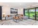 Spacious living room with a comfortable sectional sofa, stylish decor, and sliding glass doors to the backyard at 1959 Longliner Loop, Wesley Chapel, FL 33543