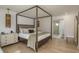 Elegant primary bedroom features a four-poster bed, light wood floors, and ensuite bathroom with shower at 2395 Campbell Rd, Clearwater, FL 33765