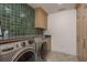 Well-equipped laundry room with modern washer/dryer, green tile backsplash, and custom cabinetry at 2395 Campbell Rd, Clearwater, FL 33765