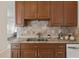 A close-up of the kitchen countertop with stainless steel sink and mosaic backsplash with wooden cabinets at 2616 Tottenham Dr, New Port Richey, FL 34655