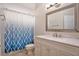 Bathroom features white vanity, tile floors, blue-patterned shower curtain and neutral walls at 30753 Pumpkin Ridge Dr, Wesley Chapel, FL 33543