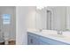 Bathroom featuring double sinks with light blue cabinets, a toilet, and a large mirror at 33306 Castaway Loop, Wesley Chapel, FL 33543