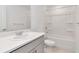 Bright bathroom features a white vanity with quartz countertop, shower over tub, and white tiling at 34234 Polacca Ln, Wesley Chapel, FL 33543