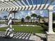 View of the community cornhole lawn area from beneath a shaded pergola, perfect for outdoor fun and relaxation at 34234 Polacca Ln, Wesley Chapel, FL 33543