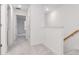 Bright hallway featuring carpeted floors, white walls, doors, and wooden railing on the staircase at 34234 Polacca Ln, Wesley Chapel, FL 33543