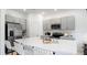 Modern kitchen features gray cabinets, stainless steel appliances, quartz countertops and a large center island at 34234 Polacca Ln, Wesley Chapel, FL 33543