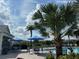 Community pool with shaded lounge chairs, tables, palm trees, and outdoor kitchen, perfect for relaxation and entertainment at 34234 Polacca Ln, Wesley Chapel, FL 33543