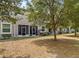 Backyard view of home with screened in porch and seating below a shady tree at 3901 Silverlake Way, Wesley Chapel, FL 33544