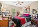 A bedroom with a ceiling fan, large window, and a bright red and black bedspread at 3901 Silverlake Way, Wesley Chapel, FL 33544