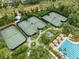 Aerial view of tennis courts and a community pool with lounge chairs and shaded cabanas at 3901 Silverlake Way, Wesley Chapel, FL 33544