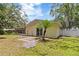 This backyard features a patio, lawn, screened-in porch, mature trees, and a privacy fence at 39721 Meadowood Loop, Zephyrhills, FL 33542