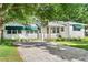 Charming white home with green awnings and a beautiful brick driveway framed by mature trees and lush landscaping at 4616 S Matanzas Ave, Tampa, FL 33611